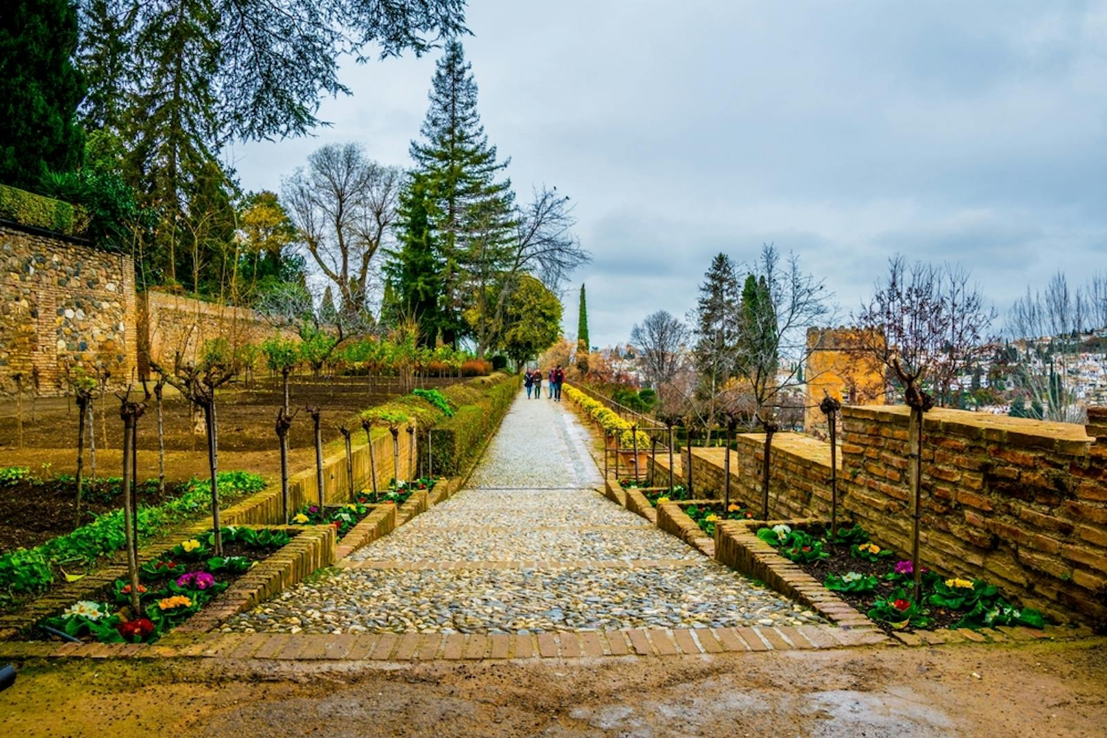 Paved path leading up to the Alhambra under a cloudy sky