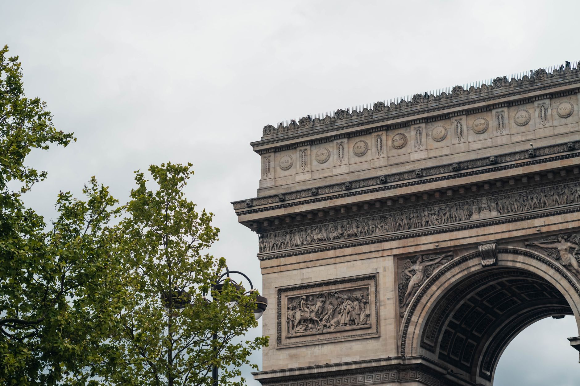 Nært billede af Arc de Triomphe under en grå himmel