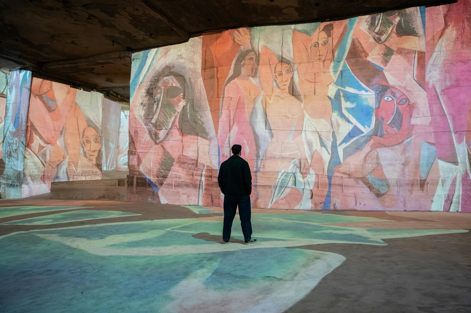 Visitor contemplating monumental projections at Les Carrières des Lumières