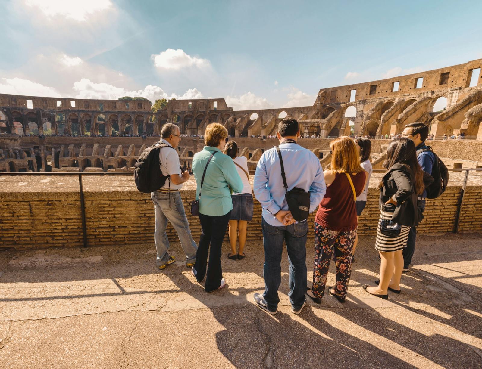 Turistas observando o Coliseu dos degraus ensolarados