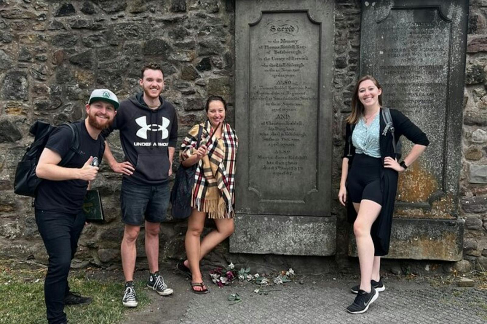 Vier lächelnde Touristen vor den Steinen des Edinburgh Castle